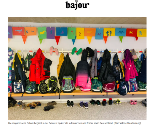 Schulgarderobe mit Jacken und Schulranzen als Symbol