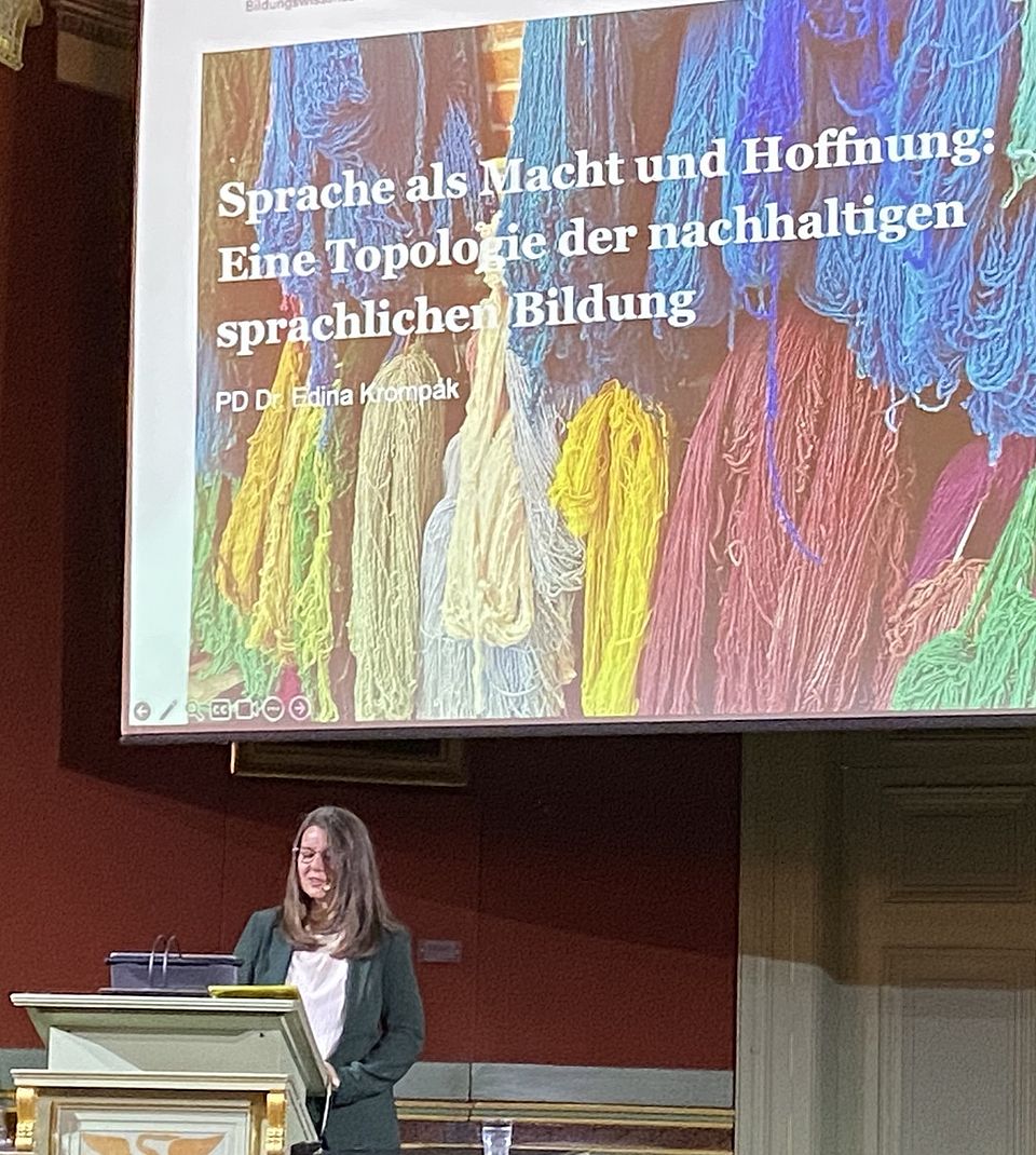 Edina Krompák am Rednerpult vor der ersten Folie, auf der der Titel ihrer Antrittsvorlesung zu sehen ist
