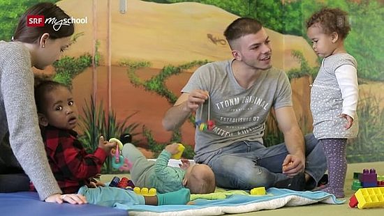 Szene aus dem verlinkten Film - junger Erzieher in der Krippe mit Kindern