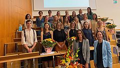 Gruppenfoto der Absolvent*innen in einem Hörsaal
